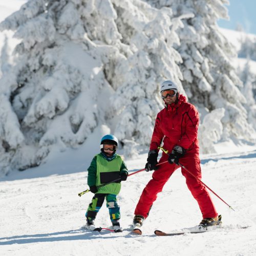 Ski instructor teaching little boy skiing
